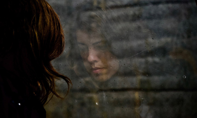 A lady and her reflection in a glass.