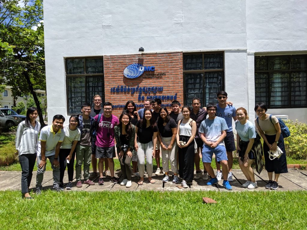 A group of students posing for a picture in front of a DMC (Department of Media and Communication) building in Phnom Penh, Cambodia. 