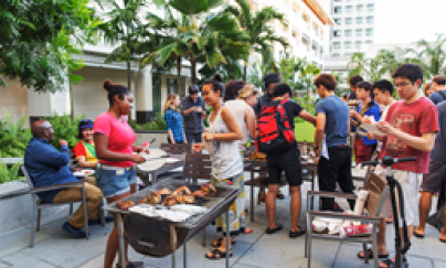 People gathering, talking to each other, and barbecuing at the Elm Courtyard.