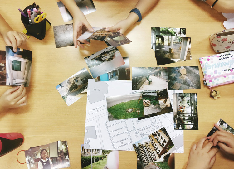 People's hands holding multiple photos of buildings and its facilities with different sizes and shapes arranged on a table.