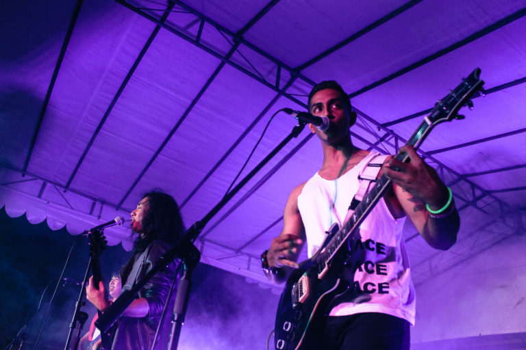 Two students playing guitar and singing on stage in a band performance during Tape Days. 